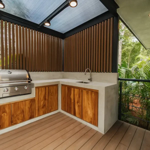 Outdoor kitchen with built-in BBQ at Manuel Antonio Tree House Villa featuring covered terrace and jungle surroundings.