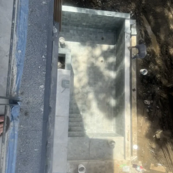 Tiled plunge pool under construction with integrated steps and visible drainage points.