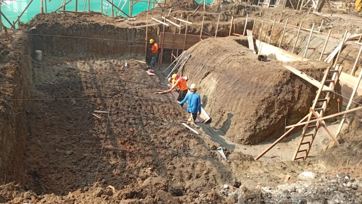 Workers manage a large deep excavation area, stabilizing soil for the complex foundation of the Manuel Antonio luxury tree house.